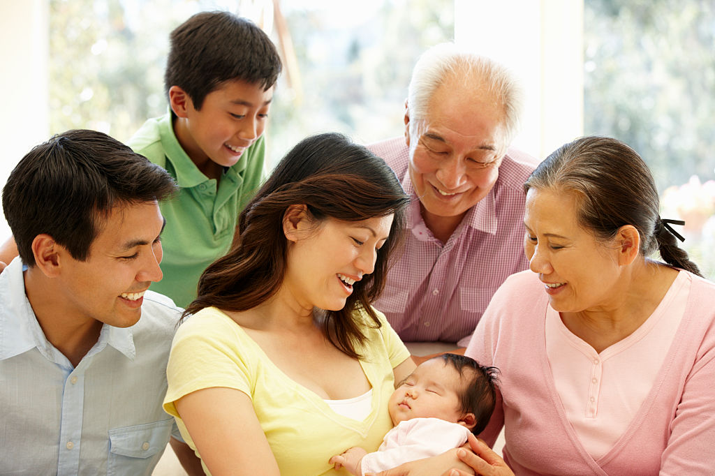 Three generations of a family gathers around a baby